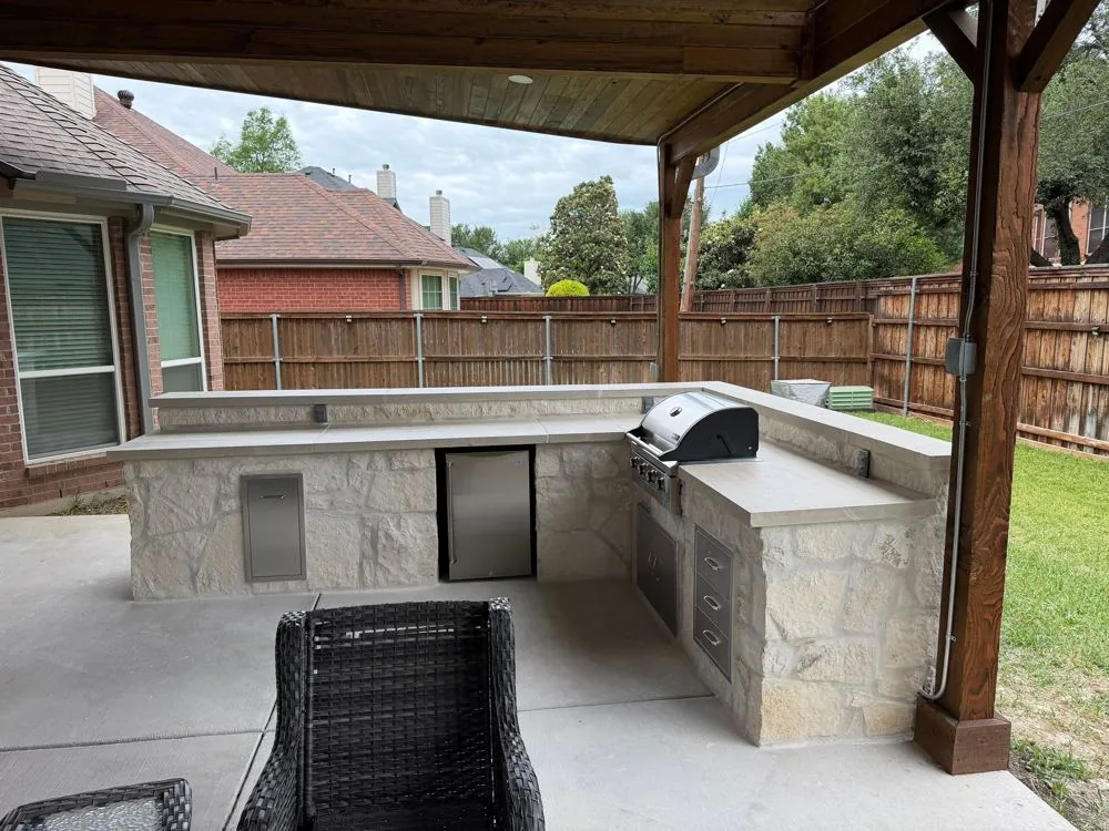 Stone outdoor kitchen with a built-in grill under a cedar cover