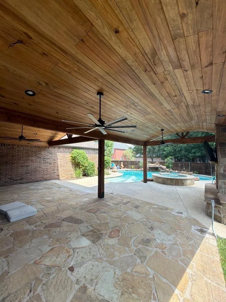 Stained wood patio cover over a flagstone pool deck