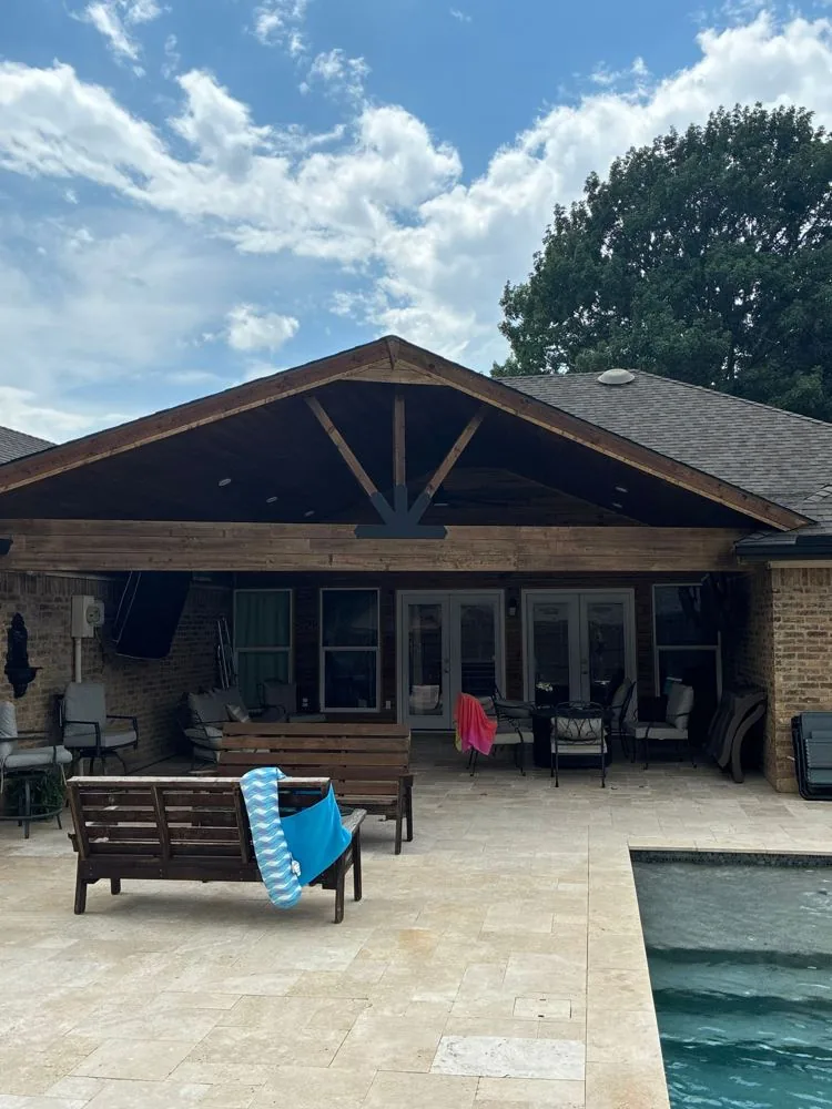 Covered stone patio beside a swimming pool