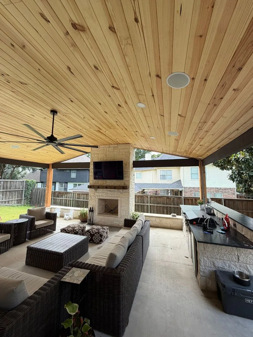 Enclosed cedar-ceiling outdoor living room with fireplace, TV and kitchen