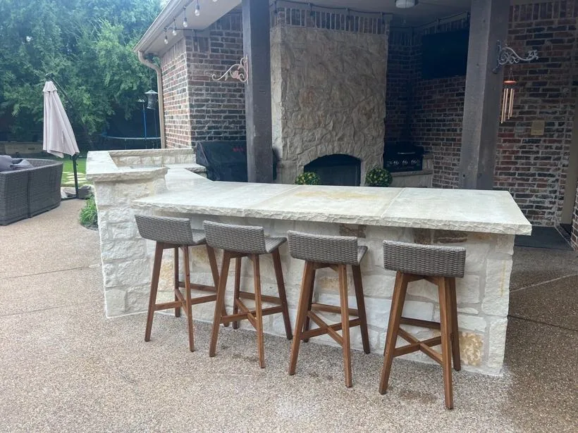 Stone outdoor bar with seating and a fireplace